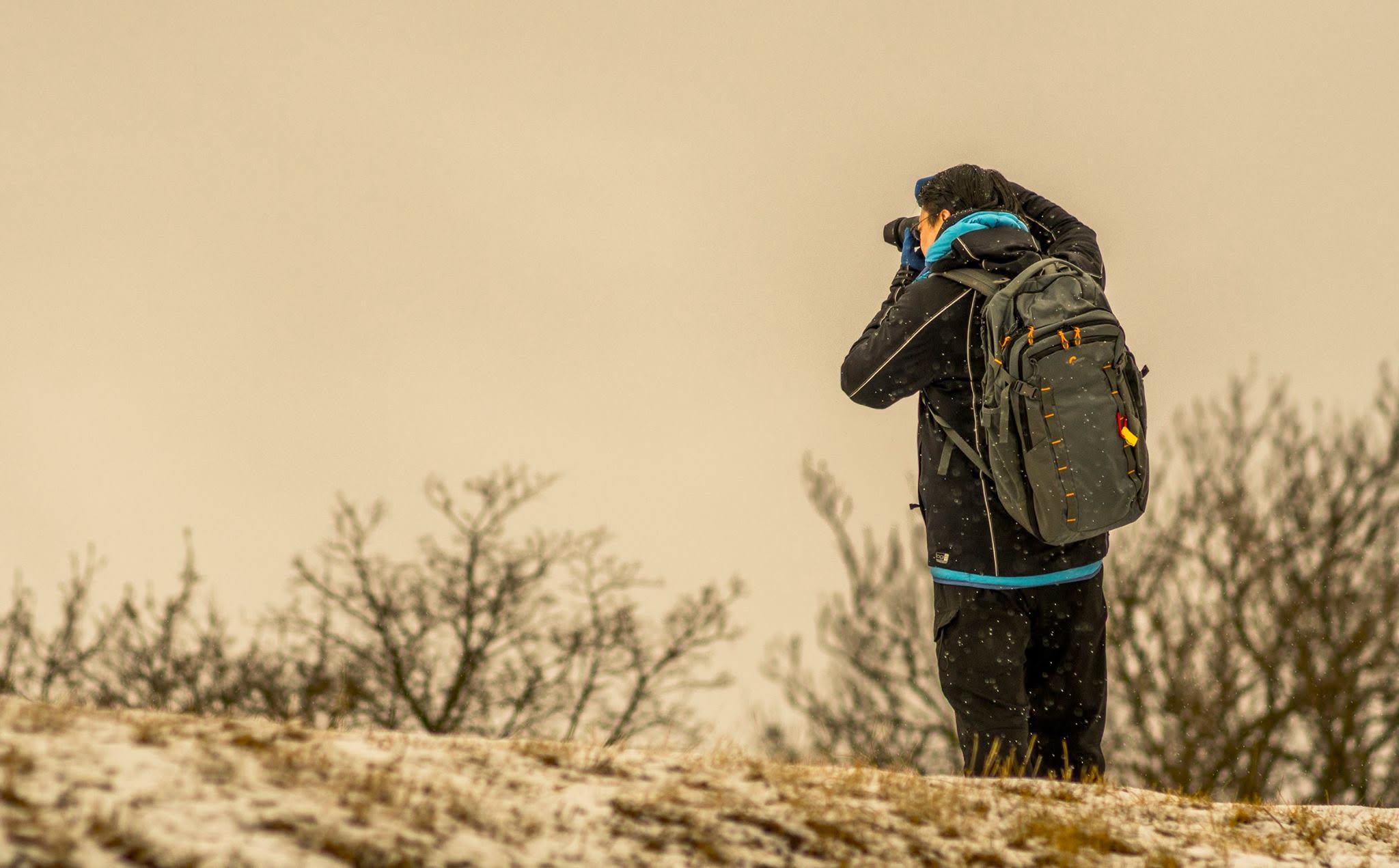 Tero Syväniemi photographing on a snowy hill