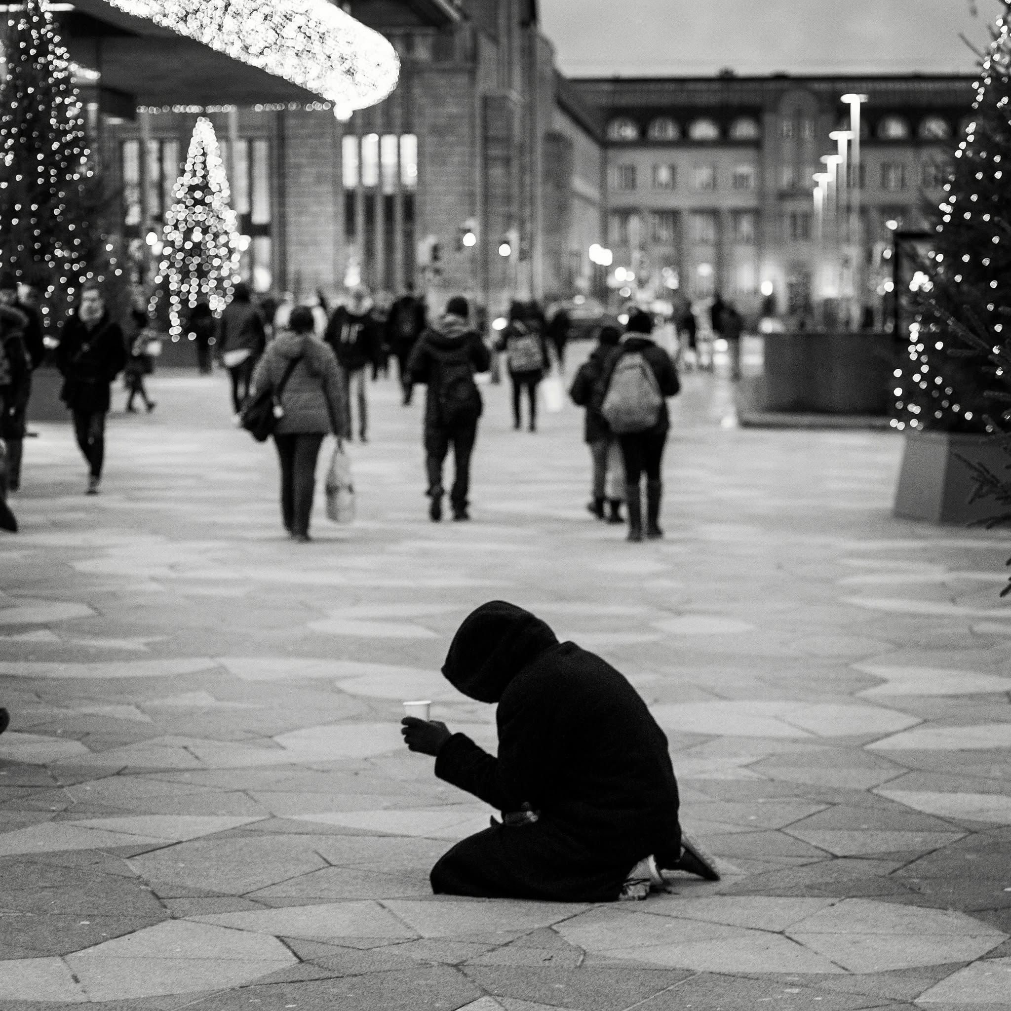 Lone hooded figure in a festive winter square