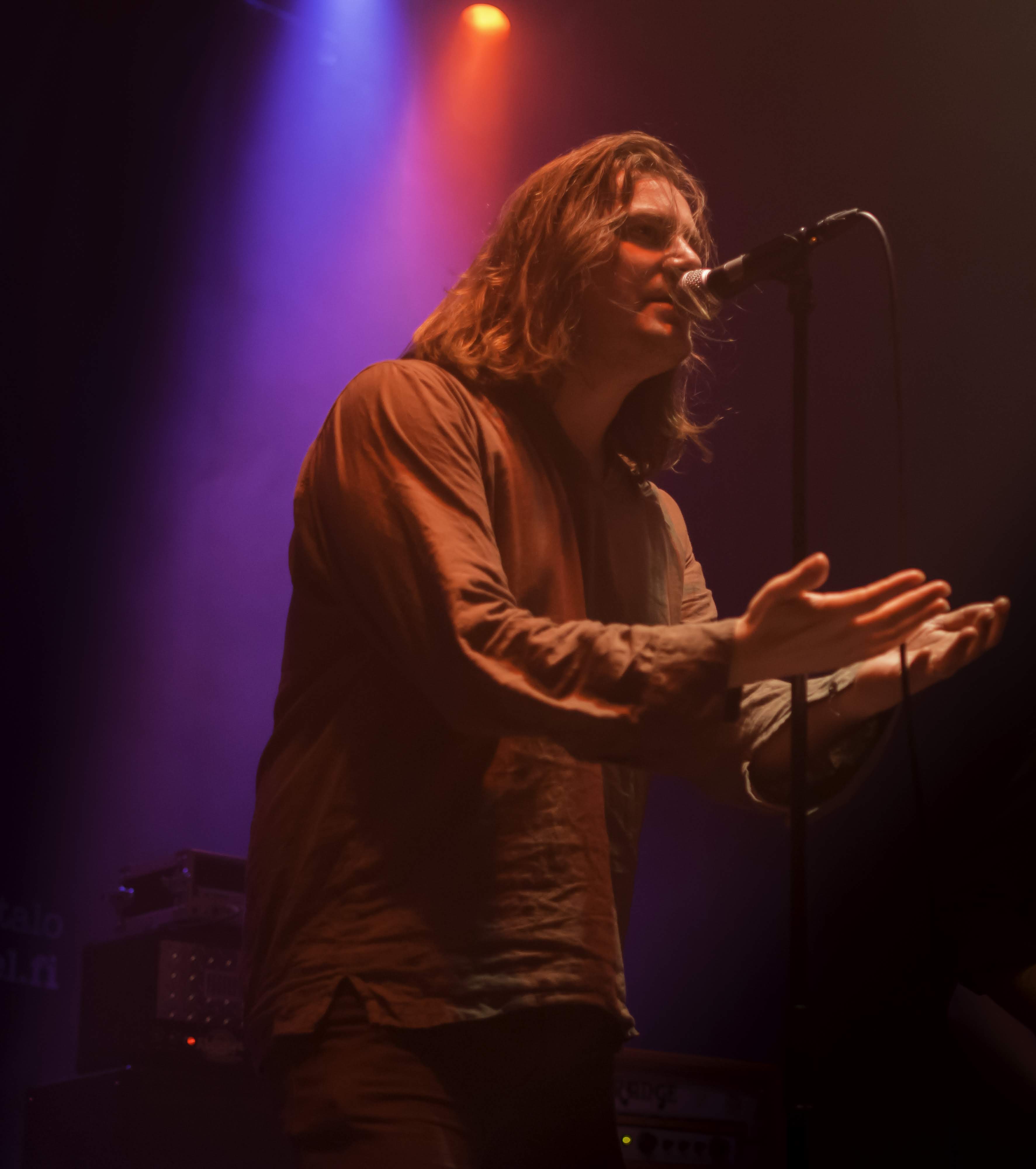 Indie rock singer under purple and orange stage light